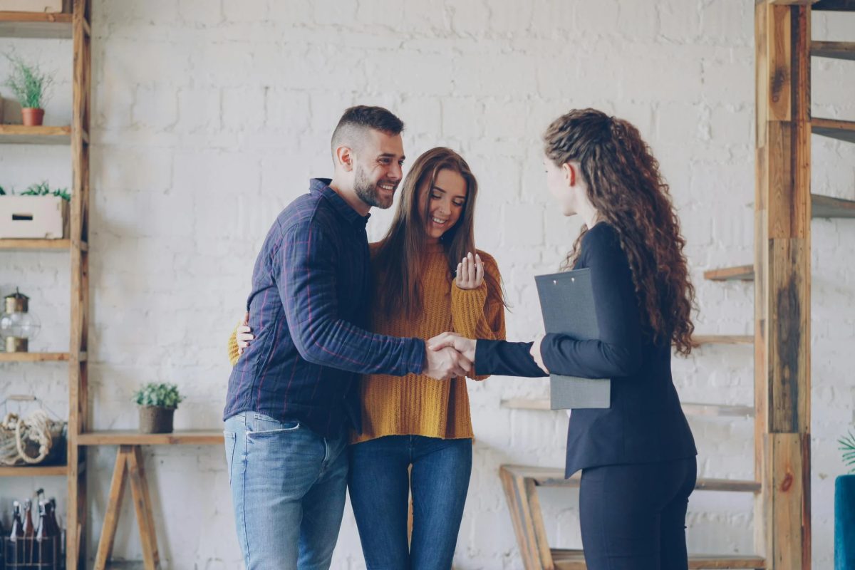 A couple shaking hands with their agent after an offer is accepted